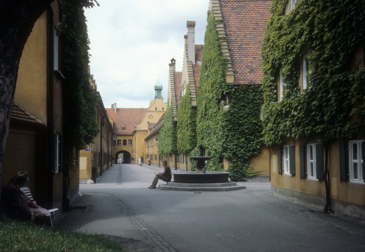 Augsburg am 25. Juni 1980: Die lteste Sozialsiedlung der Welt liegt in Augsburg. 1516 stifteten die Fugger diese Stadt in der Stadt fr schuldlos verarmte Brger. Die Siedlung umfasst 67 Huser, eine Kirche und einen Brunnen.