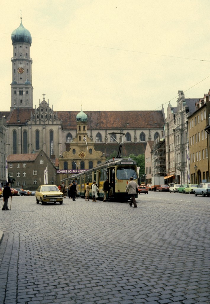 Augsburg am 26. Juni 1980: Ulrichsplatz / St. Ulrichskirche (evangelisch) mit Barockfassade und Zwiebelturm aus den Jahren 1709 bis 1710 / St. Ulrich und Afra (katholisch). Die Baugeschichte der katholischen Basilika begann 1474; bis 1762 setzte der Wiederbau / die Neueinrichtung der grossen sptgotischen Kirche fort. Im Jahre 1762 geschah eine Umgestaltung der Basilika im Stile der Rokoko. Nach dem Zweiten Weltkrieg folgten Wiederaufbau, Renovierungs- und Umgestaltungsarbeiten. 