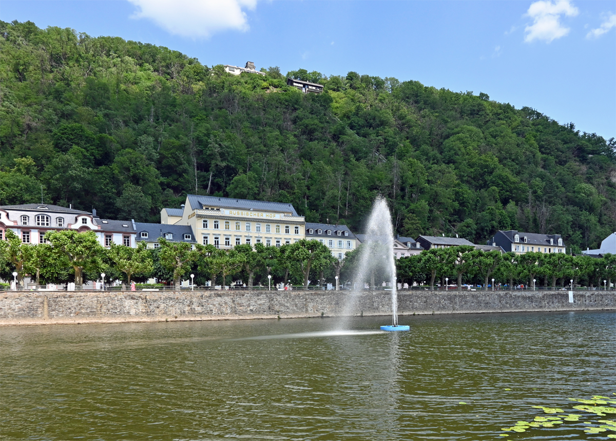 Bad Ems - der Lahn-Springbrunnen, dahinter der  Russischer Hof  und auf dem Bergrcken die Bergstation der Kurwaldbahn - 11.06.2023