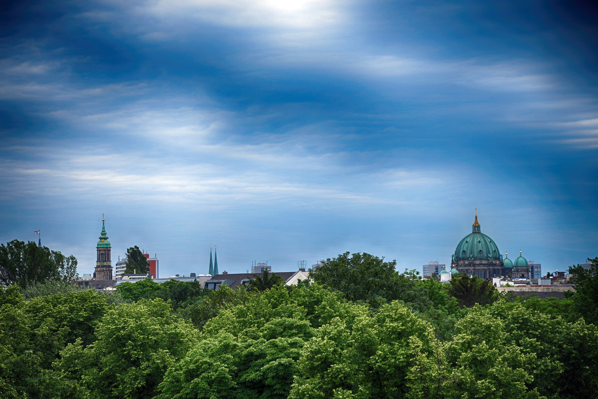 Blick auf Berlin Mitte vom Aussichtsturm an der Gedenksttte Berliner Mauer in Gesundbrunnen. Die Bume im Vordergrund stehen auf dem St. Elisabeth Friedhof. Aufnahme: 8. Juni 2019.