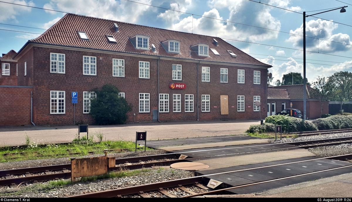 Blick auf ein Gebude der Post Danmark A/S, ein dnisches Postunternehmen, am Bahnhof Padborg st (DK).
Aufgenommen im Gegenlicht.
(Smartphone-Aufnahme)
[3.8.2019 | 11:26 Uhr]