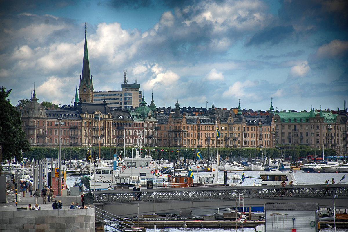 Blick auf Stockholm von Skeppsbron an der Altstadt Gamla Stan.  Im Vordergrund sieht man die Brcke Skeppsholmsbron und im Hintergrund die Kirche Oskarskyrkan.
Aufnahme: 25. Juli 2017.