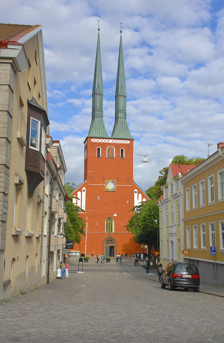 Blick auf die Turmfassade des roten Domes in Vxj. Die Innenstadt wird dominiert von dem aus dem 14. Jahrhundert stammenden Dom, der im Lauf der Jahrhunderte mehrmals umfassend restauriert wurde. An seiner Ostseite steht ein Runenstein. Sdlich des Doms erstreckt sich der Linn-Park. 
Aufnahme: 19. Juli 2017.