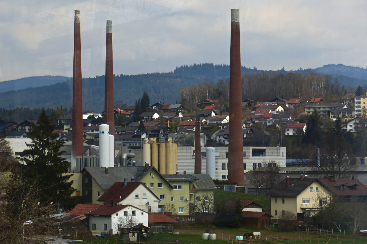 Blick auf Zwiesel mit den bekannten 3 Schornsteinen, fotografiert aus dem fahrenden Zug heraus aus Richtung Bodenmais. 10.04.2016