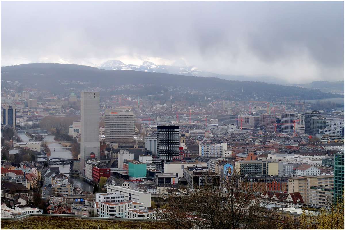 Blick vom Kferberg ber Zrich -

In Bildmitte deutlich erkennbar das schwarze Wohnhochhaus des Lwenbru-Areals. Weiter links der welthchste Getreidesilo der Swissmill an der Limmat. Rechts in Bildmitte die groen Baublcke des Entwicklungsgebietes 'Europaallee.' Darber erkennbar eine Ecke des Zrichsees. Im Hintergrund lassen die Schauerwolken einen Ausschnitt auf die Alpen zu.

13.03.2019 (M)