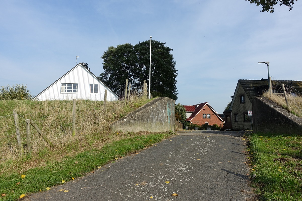 Blick in den Ort Hetlingen in der Haseldorfer Marsch am 15.10.2019: Durchfahrt am alten Winterdeich, hier wurden bis zur Fertigstellung des Landesschutzdeiches (Bauzeit 1945-1978) Bretter in die links und rechts in den Beton eingebrachten Schienen gesteckt, um den Deich zu schlieen /