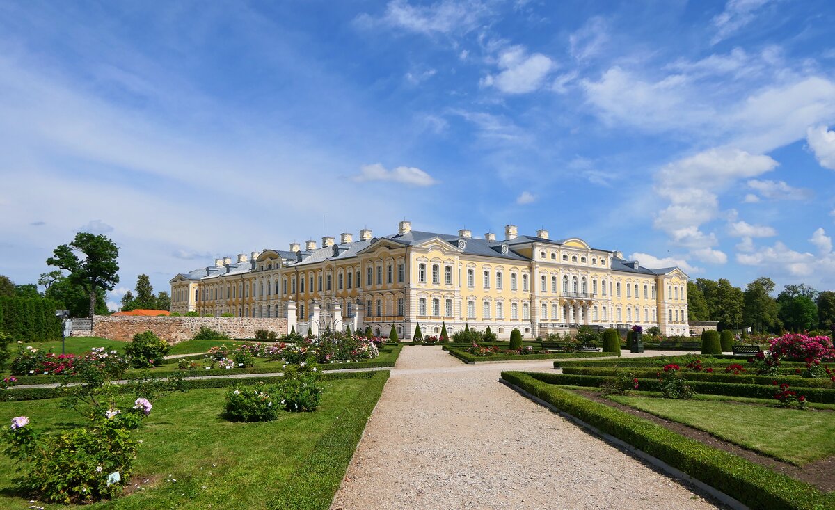 Blick ber den Rosengarten auf das Barockschloss Ruhental (Rundāles pils) bei Bauska (LV). Das Bauwerk wurde im 18. Jhd. nach Entwrfen des Architekten Bartolomeo Francesco Rastrelli geplant, der auch fr den Winterpalast der Eremitage in St. Petersburg verantwortlich zeichnet. Vorbild fr den Bau war mitunter der Palast Ludwigs XIV., weshalb Rundāles pils auch als  baltisches Versailles  gilt. Aufgenommen am 15.07.2025, an dem sich der lettische Sommer von seiner besten Seite prsentierte.
