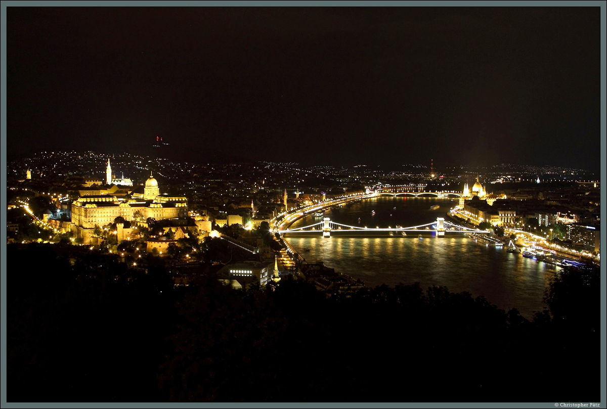 Budapest bei Nacht: Links der Burgberg mit dem Burgpalast und der dahinter liegenden Matthiaskirche. In der Mitte fliet die Donau, welche vorn von der Kettenbrcke und im Hintergrund von der Margaretenbrcke berspannt wird. Am rechten Flussufer ist auerdem das Parlamentsgebude erkennbar. (Blick vom Gellertberg, 15.08.2014)