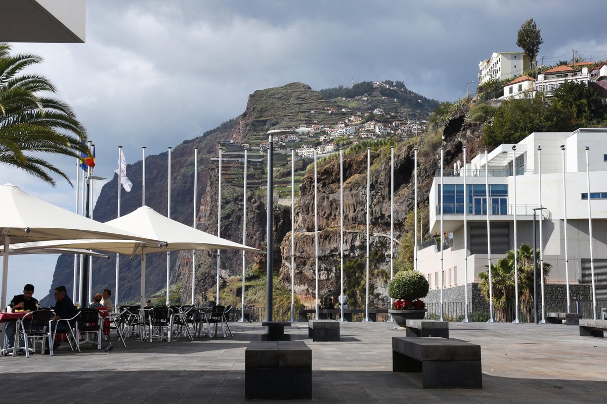CÂMARA DE LOBOS (Concelho de Câmara de Lobos), 30.01.2018, auf der  Flaniermeile  vor der Kirche; rechts die Gemeindebibliothek und das Pressemuseum, im Hintergrund der Felsen mit dem Aussichtspunkt Cabo Girão