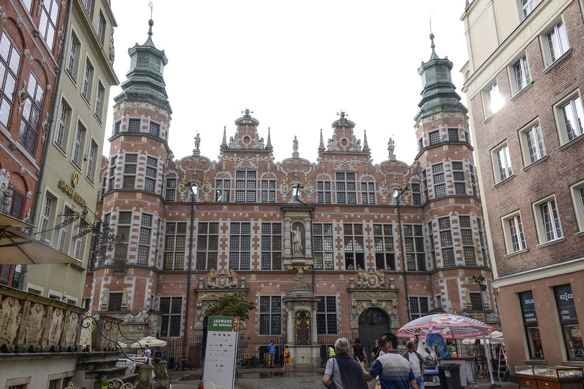 Danzig / Gdansk. Das Groe Zeughaus (polnisch: Wielka Zbrojownia) das als Waffenarsenal diente, ist ein typisches Beispiel fr den flmischen Manierismus in Danzig. Die Fassade auf beiden Seiten des Gebudes ist in Giebel gegliedert: am Holzmarkt vier, an der stlichen Frontseite zur Jopengasse zwei. Daran schlieen sich zwei Trme an den Seiten an. Die Spitzen der Giebel sind mit Bronzeplastiken von explodierenden Kanonenkugeln geschmckt, die deutlich auf den Verwendungszweck des Gebudes hinweisen. Aufnahme: 14. August 2019.