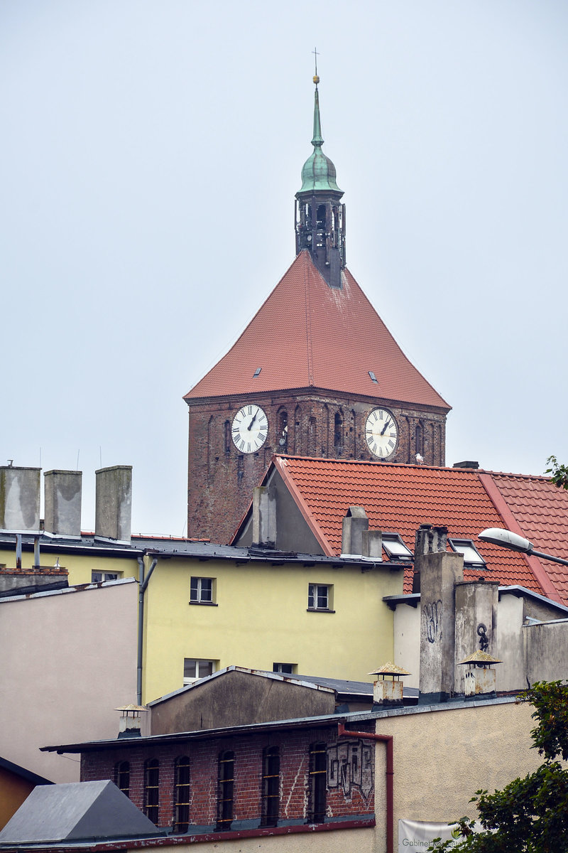 Darłowo in Hinterpommern - Der Turm von Rügenwalder Marienkirche hinter Hausdächern in der Innenstadt. Aufnahme: 22. August 2020.