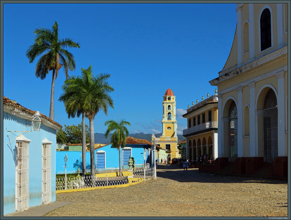 Das historische Zentrum von Trinidad bildet der Plaza Mayor vor Kirche der heiligen Dreifaltigkeit (rechts). Im Hintergrund zu sehen ist der Turm des Klosters Convento de San Francisco de Asis, das ein Revolutionsmuseum beinhaltet. (24.03.2017)