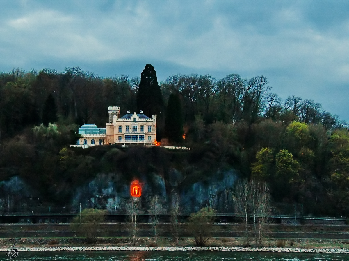 Das neugotische Schloss Marienfels und darunter eine angeleuchtete halbrunde Grotte, in der eine Mutter-Gottes-Figur aufgestellt wurde. (Remagen, April 2021)