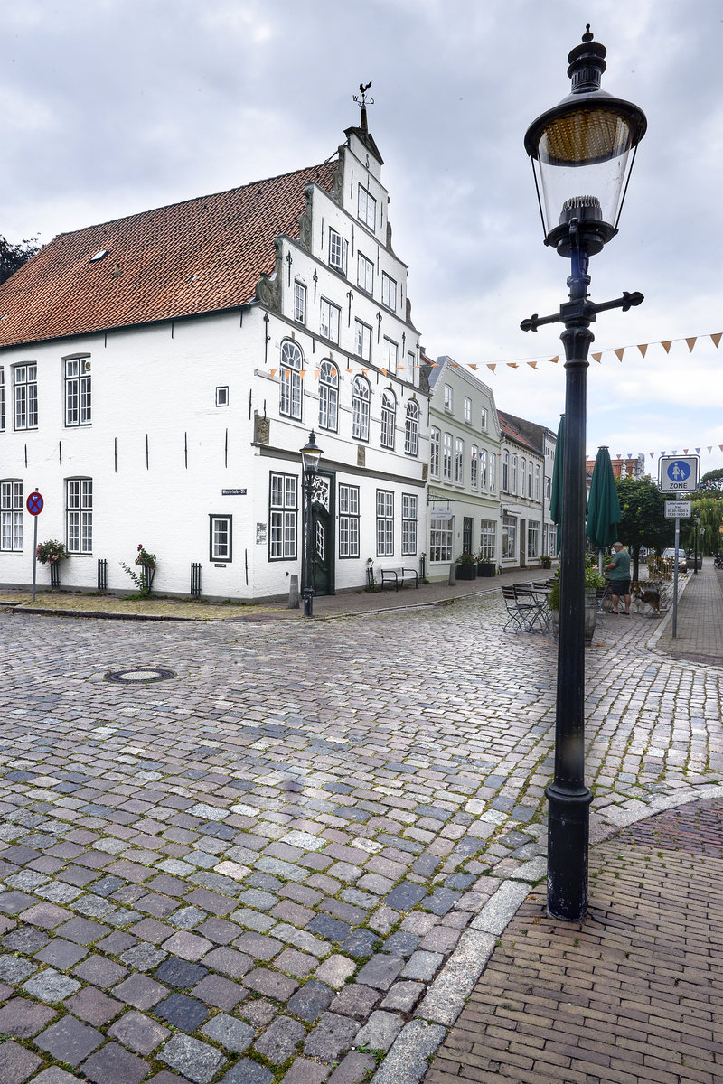 Das Paludanushaus in Friedrichstadt. Das Haus wurde 1637 vom Kaufmann Godefritius Paludanus erbaut. Die ursprnglich vorhandenen zwei Giebel wurde 1840 unter einem Dach zusammengestellt, die alten Sandsteinverziehungen weiter verwendet. Nur der Giebelanschlu mit Obelisk und Attika wurde damals errichtet. Neben der prchtigen Rokokotr befindet sich eine eingemauerte Kanonenkugel der Beschieung von 1850. Aufnahme: 9. Juli 2019.