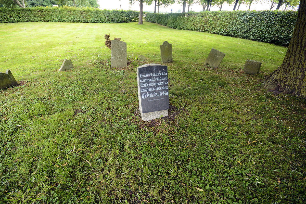 Der Alte Jdische Friedhof Friedrichstadt. Das Friedhofsgelnde ist frei zugnglich. 17 alte Grabsteine sind dort noch zu finden. 15 sind um eine Gedenktafel herum gruppiert, zwei stehen abseits in einer Ecke. Aufnahme: 9. Juli 2019.