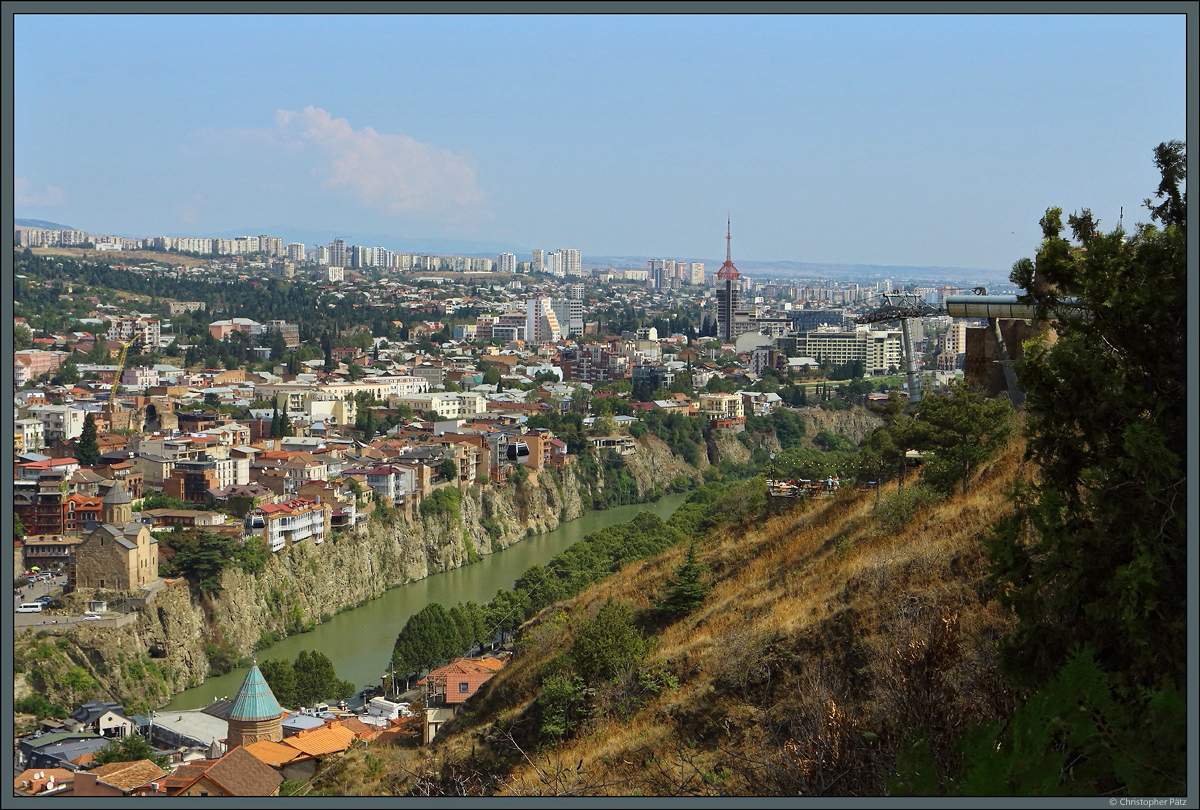 Der Fluss Mkvari hat sich unterhalb der Narikala-Festung in die Felsen hineingegraben. Direkt am Steilufer stehen die alten Wohnhuser des Stadtteils Avlabari. Seit 2012 verbindet eine Seilbahn den Stadtteil mit der Festung. Links ist die ber 700 Jahre alte Metekhi-Kirche zu sehen. (Tiflis, 17.09.2019)