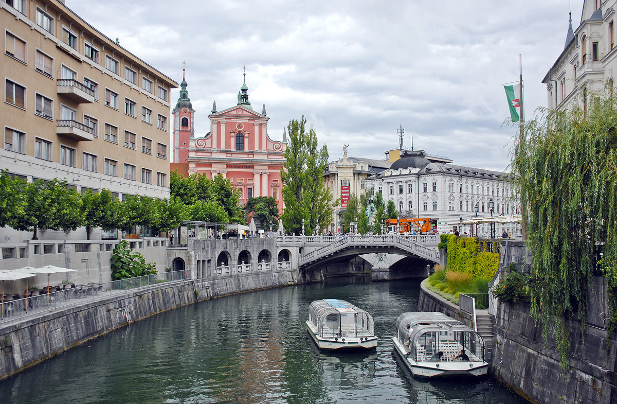 Der Fluss Sava in Ljubljana. Im Hintergrund ist die rote Mari-Verkndigung-Kirche (Slowenisch: Cerkev Marijinega oznanjenja) zu sehen. Aufnahme: 1. August 2016.