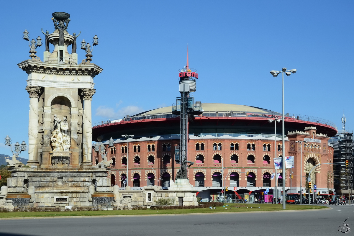 Der Plaza de Espaa mit dem barocken Denkmal  Espaa Ofrecida a Dios  (Gott geweihtes Spanien) und der ehemaligen Stierkampfarena im Hintergrund ist einer der bekanntesten Pltze von Barcelona. (Februar 2013)