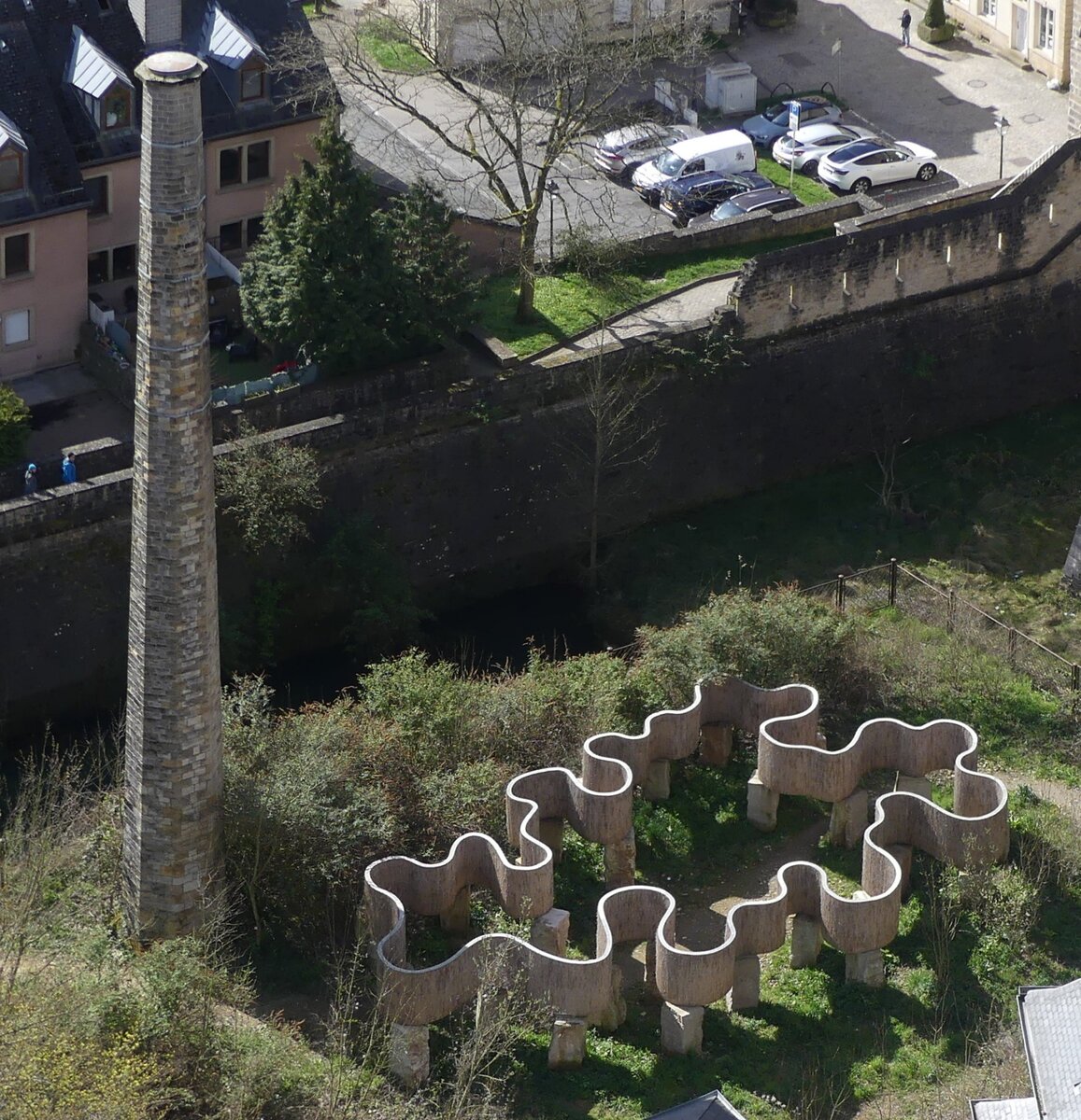 Der Schornstein F�ngerl�k im Pfaffenthal ist der einzige �berrest des Wasserwerkes das bis 1940 von hier mit einer Pumpstation angetrieben von einer Dampfmaschine das Wasser zum h�hergelegenen Limpertsberg hochpumpte. Die Skulptur neben dem Schornstein ist von der LUGA von letzten Jahr. Das Luga-Solum ist ein Schilfrohrgeflecht auf luxemburgischen Sandstein. Aufgenommen von der Roten Br�cke (Pont Grand duschesse Charlotte) in der Stadt Luxemburg 01.04.2026