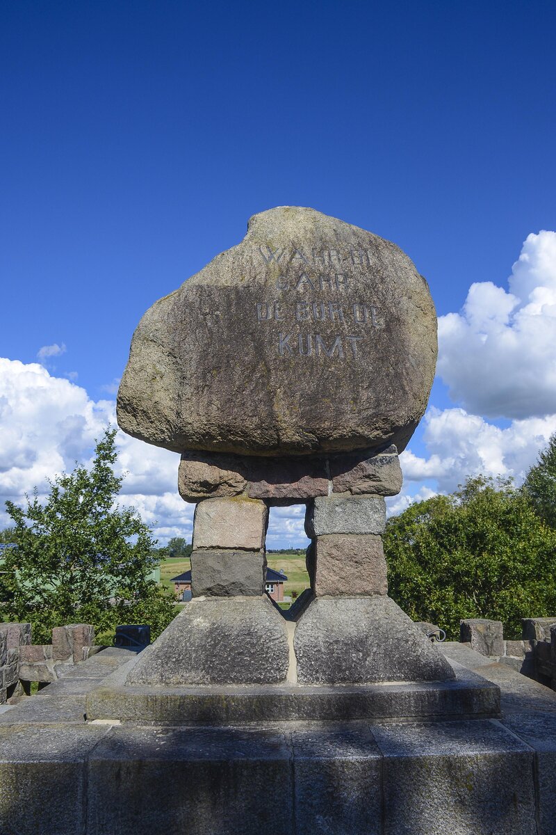 Die Dusenddwelswarf mit Denkmal in der Nhe von Hemmingstedt in Dithmarschen. Der Kieler Architekt Wilhelm Voigt (1857–1916) stellte einen Findling ins Zentrum seines Werks und lie auf der Nordseite das Motto der Dithmarscher anbringen: WAHR DI / GARR / DE BUR DE / KUMT (Nimm dich in Acht, Garde, der Bauer, der kommt). Aufnahme: 22. September 2022.