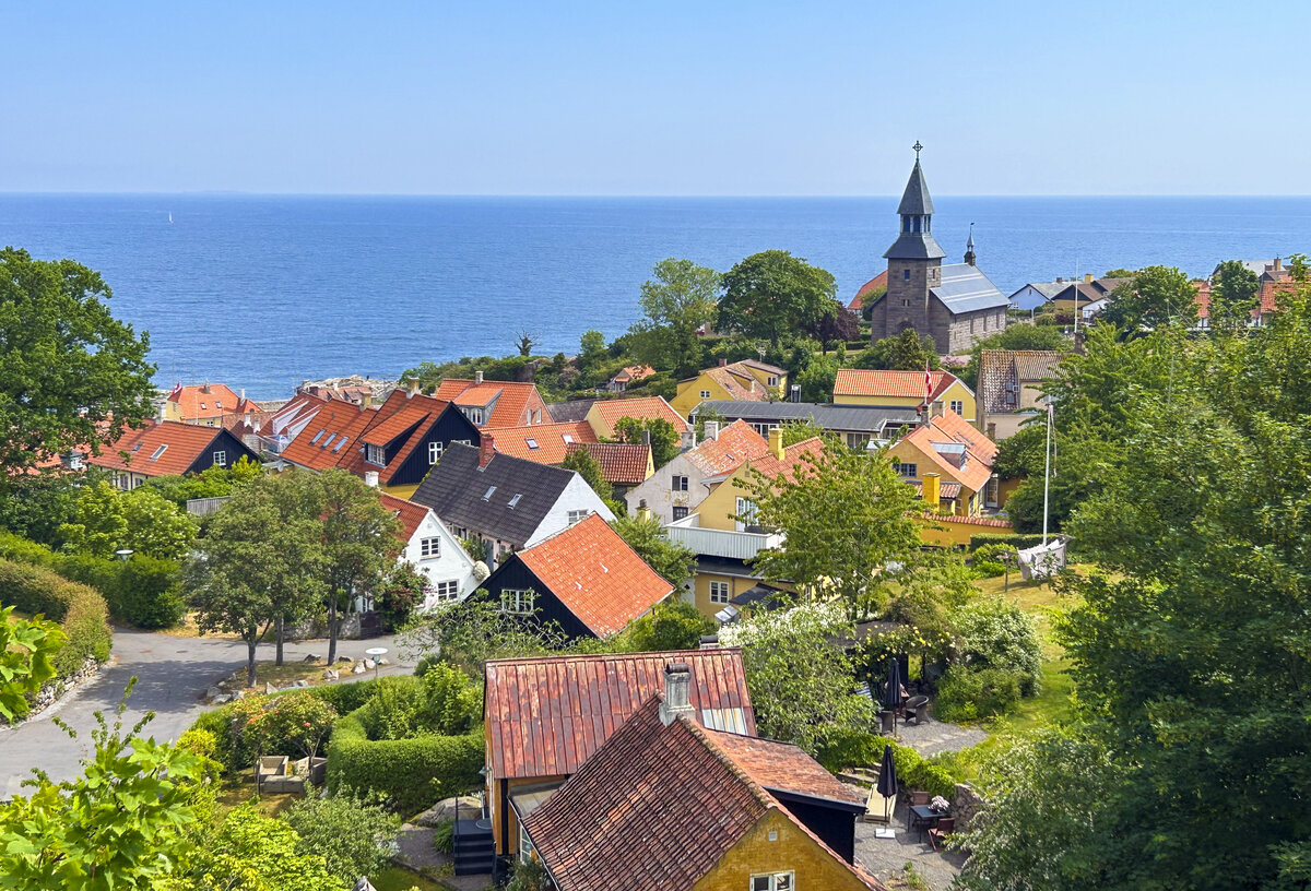 Die Innenstadt von Gudhjem von der Landesstrae Helligdomsvej aus gesehen. Aufnahme: 16. Juni 2023.