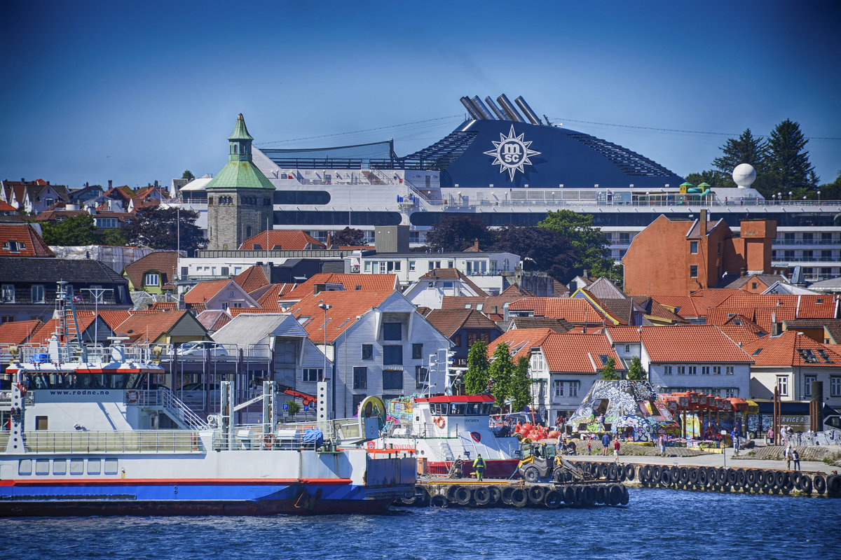 Die Innenstadt von Stavanger von der Tau-Stavanger-Fähre aus gesehen. Im Hintergrund ist ein riesiges Kreuzfahrtschiff zu sehen. Aufnahme: 3. Juli 2018.