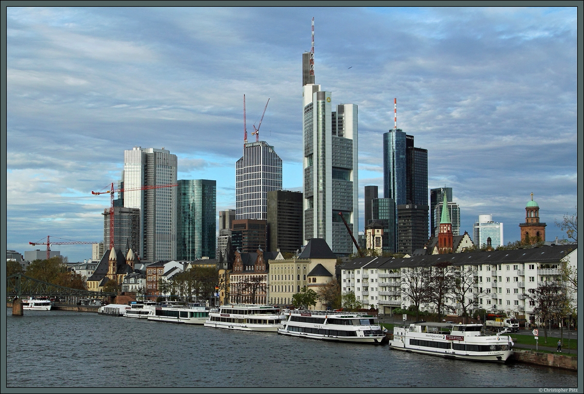 Die Skyline von Frankfurt am Main, von der alten Brcke aus gesehen. Von links nach rechts: Leonhardskirche, Eurotower, Skyper-Hochhaus, Taunusturm, Commerzbank Tower (Mitte, das hchste Gebude Deutschlands), Maintower, Alte Nikolaikirche und Paulskirche. (28.10.2013)