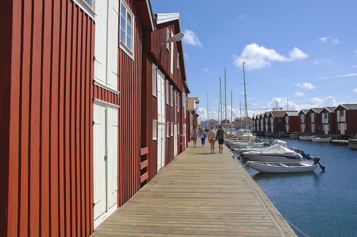 Die Smgenbryggan in Mgen ist ein fast ein Kilometer langer Holzsteg. Die Promenade direkt am Yachthafen schlngelt sich entlang der Granitfelsen dem Hafen entlang. An ihr gelegen befinden sich zahlreiche, auf Stelzen stehende Fischer- und Speicherhuser, Bootsschuppen, Restaurants, Imbisse, Boutiquen und Souvenirlden. 
Aufnahme: 2. August 2017.