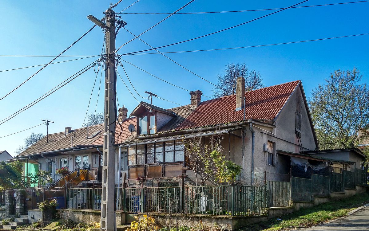 Dieses Foto habe ich in Pcs, in der Stadtteil  Erzsbettelep  (Elisabethsiedlung) gemacht. Dieser Stadteil wurde durch die Donaudampfschiffgesellschaft gegrndet. Die  Kolonie  stand aus 4 Strassen und 32 Huser. Es gab 6 kleine Wohnungen pro Haus zzgl Gartenteil und Nebengebude. Vor ca. 100-120 Jahren wurden neue Kohlenminien in der Nhe erffnet und die dort arbeitenden haben hier Wohnungen bekommen. Die Siedlung hie ursprnglich Ullmannsiedlung, genannt nach einem Leiter des Unternehmens. 1938 wurde auf Elisabethsiedlung umbenannt (von Elisabeth Amalie Eugenie von Wittelsbach Knigin genannt). Die Huser waren berdurchschnittlich ausgerstet, da Leitungswasser und Strom auch vorhanden war. In den vergangenen guten Jahrhundert wurde es nicht geregelt wie man die Gebuden/Wohnungen ndern, erweitern, umbauen oder zusammenlegen/vereinigen darf. Deswegen ist auf heutzutage das Strassenbild ganz ganz gemischt (und daher meiner Meinung nach, sehr einzigartig und interessant) geworden. Die Etagen wurden gendert, Dachgeschosse wurden eingebaut...daher findet man hier keine zwei gleiche Huser. Die groe nderungen sind um ca 1926 begonnen. Wegen der damaligen Wohnungsmangel hat die Stadt 2/3-tel der Siedlung in Miete genommen und hat unter anderem eine Kirche und Schule erbaut und geffnet. Aufnahmezeit: November 2020. 
Auf diesem Bild lohnt es sich die Dcher anzuschauen. 1Deckung = 1Besitzer = 1 Wohnung