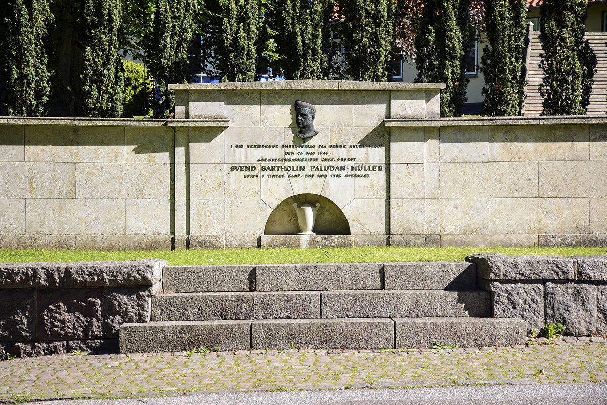 Es war frh am Morgen um 5.30 Uhr, als die Gestapo am 26. Mai 1944 am Slotsbakken 1 in Gravenstein nin Nordschleswig an die Tr von Oberst Paludan-Mller klopfte. Der Oberst widersetzte sich seiner Festnahme, und es kam zum Kampf. Oberst Paludan-Mller erschoss einen deutschen Soldaten und verschanzte sich in seinem Haus. Drei Stunden und eine Belagerung spter brannte das Haus und der Oberst war tot. In Gravenstein findet man heute diese Gedenkmauer. Auf dem Grundstck hinter der Mauer fand damals die Gestapo-Aktion statt. Aufnahme: 9. Juni 2021.