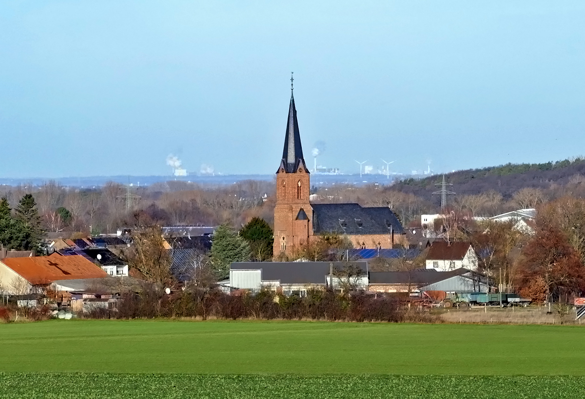 Euskirchen-Obergartzem mit Pfarrkirche St. Hubertus. Im Hintergrund  qualmende  RWE-Kraftwerke westlich von Kln - 10.12.2019