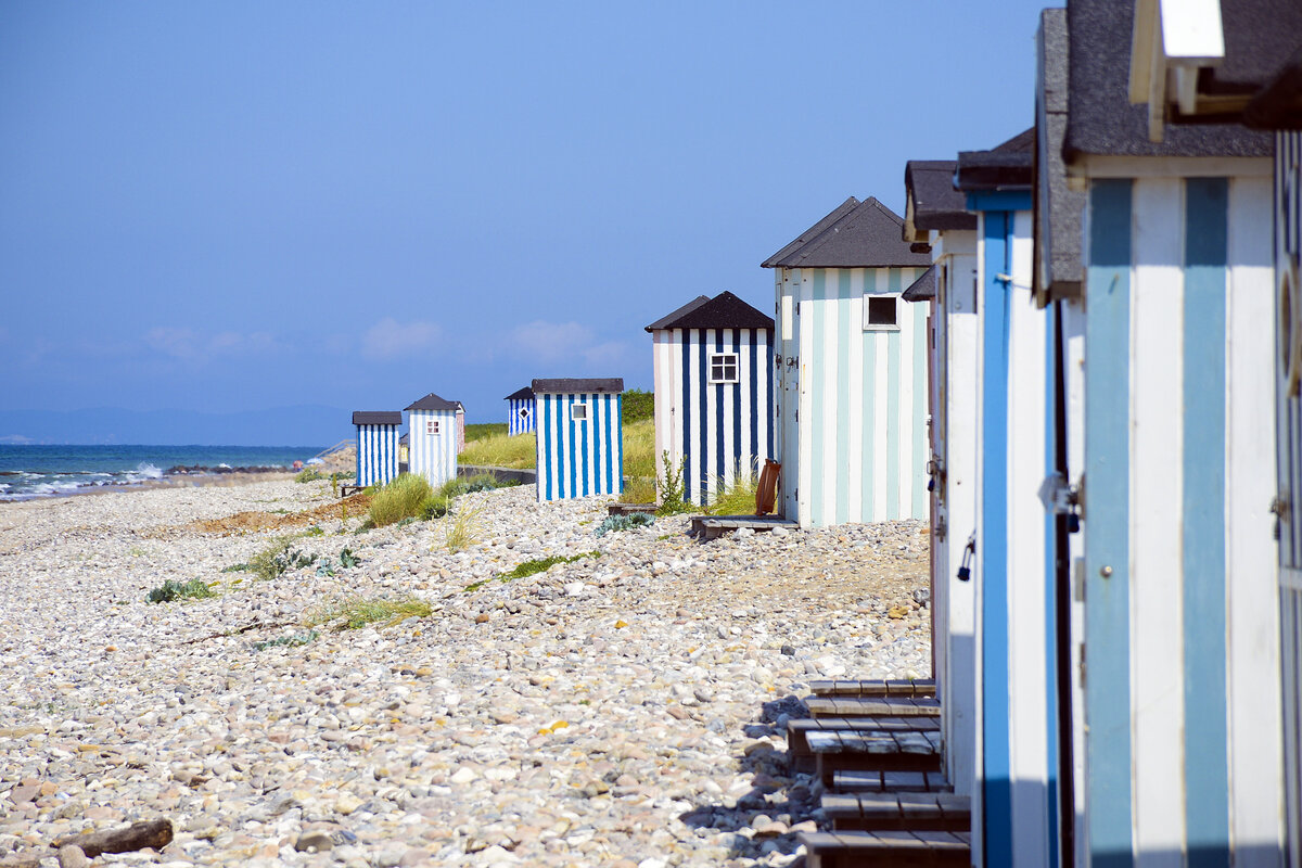 Farbenfrohe Badehuser am Strand vor Rgeleje auf Nordseeland. Aufnahme: 22. Juni 2023.