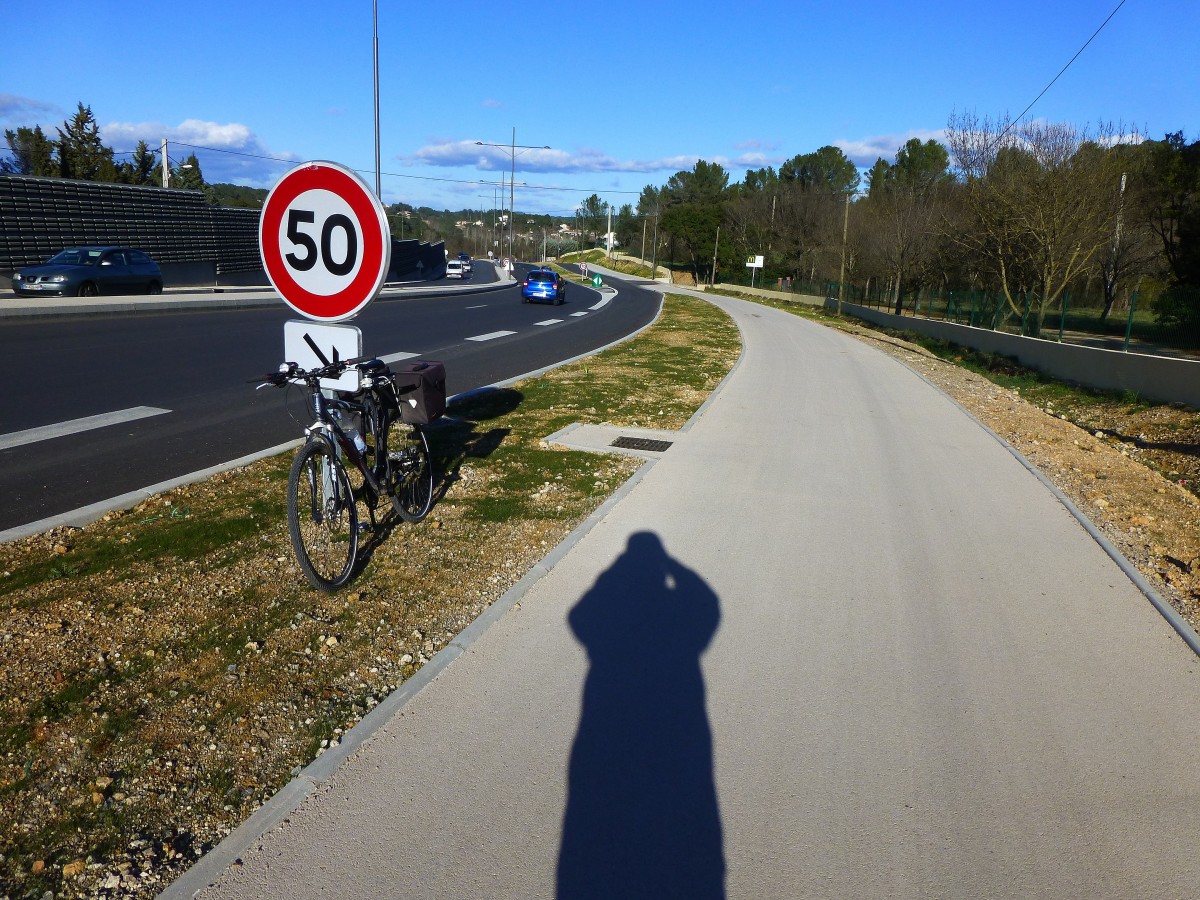 Frankreich, Languedoc, Hrault, Montpellier. Die Route dpartementale 65 (die Strasse der Kreisverkehre) wird zu einem 2x2 Boulevard intrieur auf 10km im Norden Montpelliers ausgebaut. Gleichzeitig entsteht hier ein hervorragender Radweg. Das Bild zeigt den Boulevard, den Radweg, sowie das Fahrrad (deutscher Bauart) mit einer Flasche Gerolsteiner und dem Schattenbild des Fotografen. 23.01.2014
