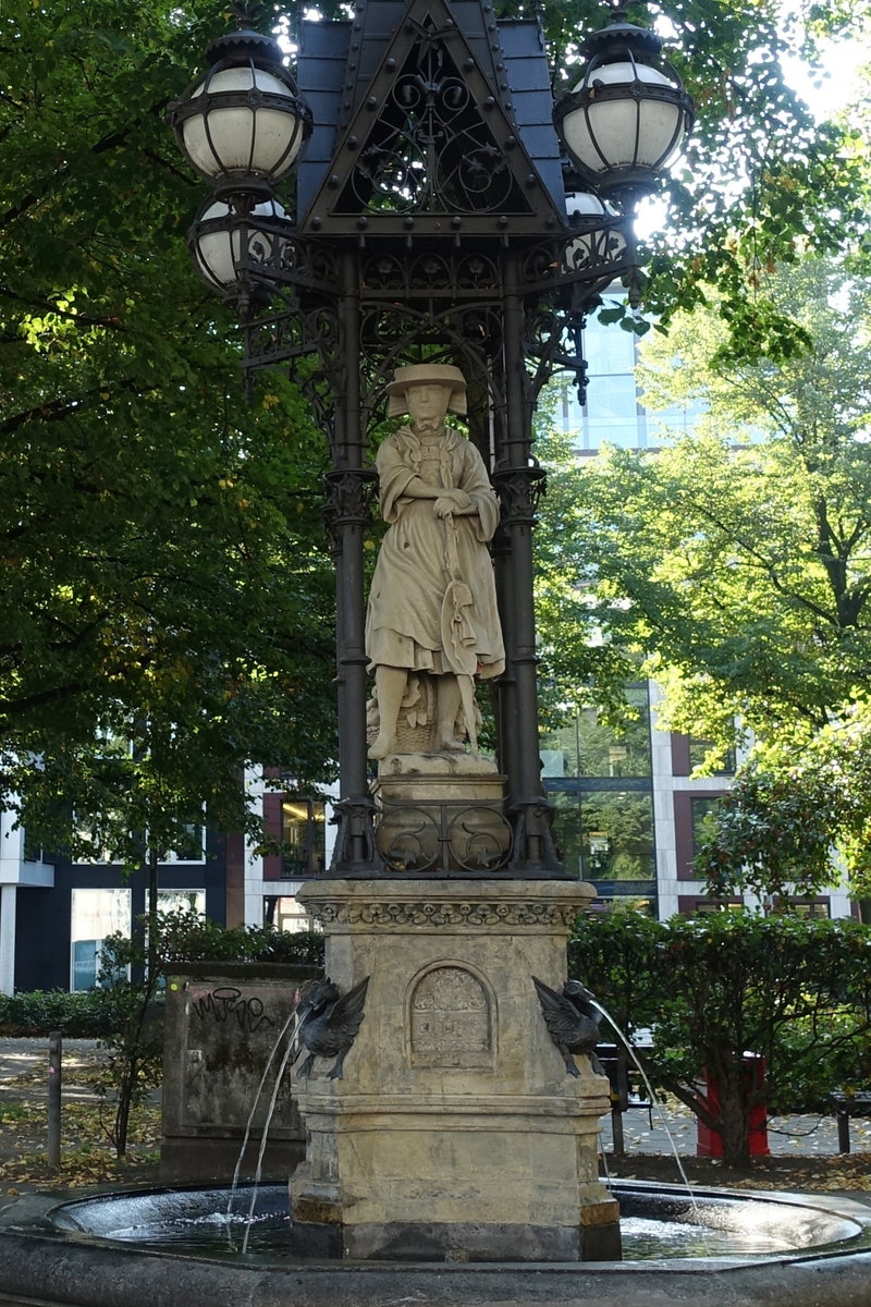 Hamburg am 1.10.2020: denkmalgeschtzter „Vierlnderin-Brunnen „ steht seit 1975 auf historischen Hopfenmarkt.
Er erinnert an die Vierlande als die Hauptlieferanten fr Hamburgs Mrkte.
Der Brunnen entstand 1878 nach Plnen von Friedrich Johann Lorenz Meyer, die Statue wurde von Engelbert Peiffer gefertigt. 
Der steinerne, im Brunnenbecken stehende, Statuensockel trgt um seine vier Seiten herum verteilt die Inschrift: „Auf dem Markt lernt man die Leute kennen“. Auf dem Sockel sitzen vier wasserspeiende Enten, die aus Bronze gefertigt sind. 2019 wurde die Restaurierung abgeschlossen.
