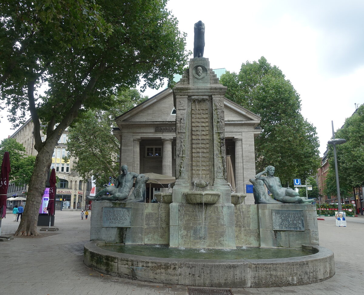 Hamburg am 1.8.2021: Der Mnckebrunnen und das dahinter liegende Gebude wurden vom damaligen Oberbaudirektor Fritz Schumacher entworfen und 1926 fertiggestellt. Die Bronzen stammen aus der Werkstatt des Knstlers Georg Wrba. Das Gebude mit den Sulen war eine ffentliche Bcherhalle und wurde 2009 in ein Kulturcaf umgewandelt. Das Ensemble entstand zum Gedenken an den Hamburger Brgermeister Johann Georg Mnckeberg (1839-1908)