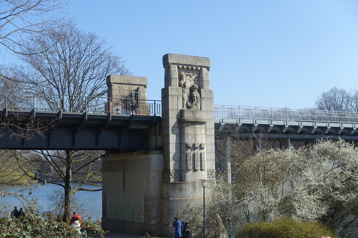 Hamburg am 27.3.2022: Nordwestliches Widerlager der Kuhmhlenteichbrcke. 
Brcke der U-Bahn Linie U3 (Ringlinie),1911/1912 erbaut, die vier mit Granit verkleideten Widerlager haben die jeweils nach auen gewandten Seiten je eine Symbol-Darstellung fr eines der vier Elemente. 
