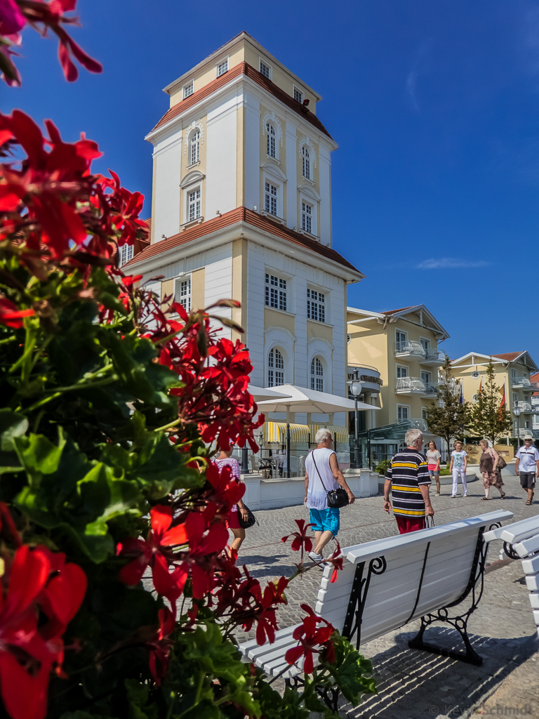 Hier ist einer der beiden Ecktrme des Kurhauses an der Strandpromenade in Binz zu sehen. Einige Touristen spazieren vorber. (26.07.2014)