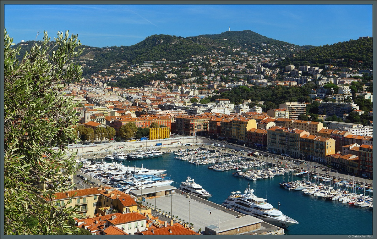 Im Hafen von Nizza liegen zahlreiche Yachten vor Anker. Dahinter beginnt der Stadtteil Riquier. Auf den Bergen im Hintergrund sind links das Observatorium und rechts der Funkturm zu erkennen. (Nizza, 26.09.2018)