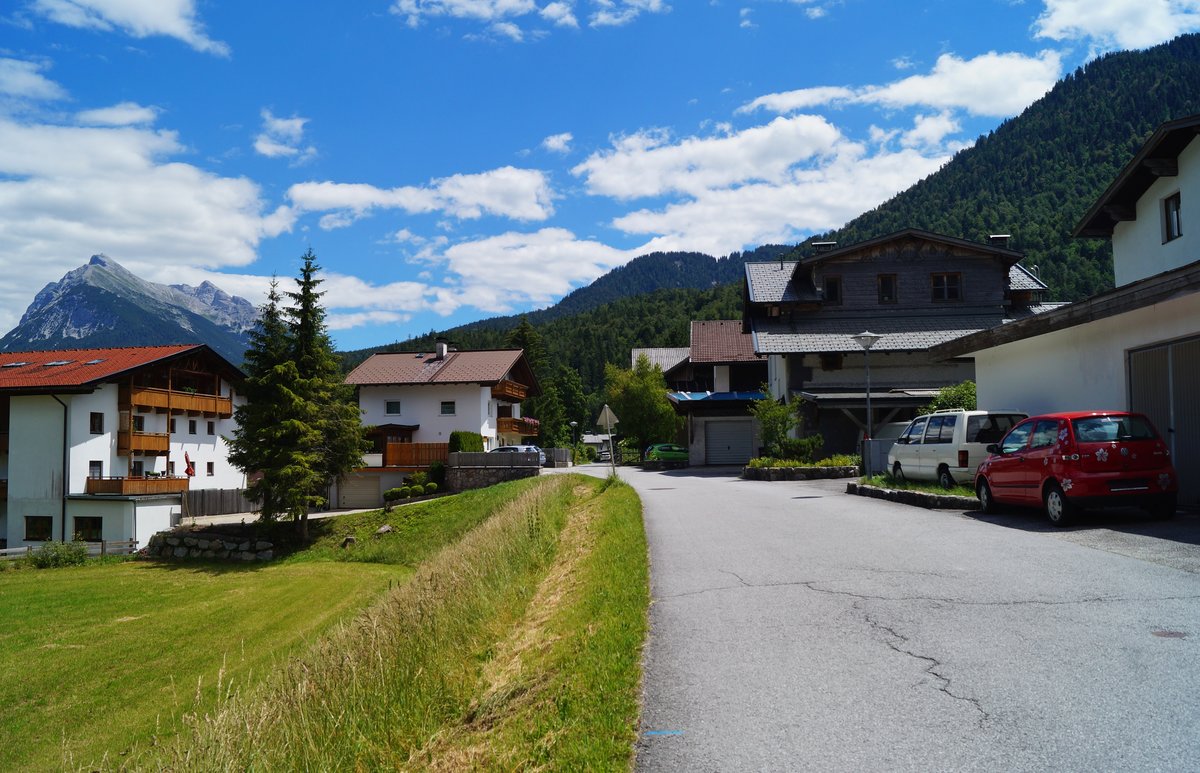 In der malerischen Ortschaft Scharnitz an der Grenze zu Deutschland (Bayern). Blick ostwrts vom Feldweg aus, unweit der Pfarrkirche gelegen. Im Hintergrund das Bergpanorama der Nrdlichen Karwendelkette. (05.07.2020)