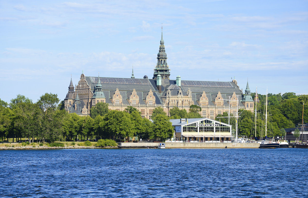 Junibacken (im Vordergrund)  ist ein Museum in Stockholm, das der schwedischsprachigen Kinderliteratur, insbesondere den Bchern Astrid Lindgrens gewidmet ist. Es befindet sich auf der Halbinsel Djurgrden. Das Nordische Museum (im Hintergrund) liegt auf der Insel Djurgrden in Stockholm und ist fr die Darstellung der Kulturgeschichte und Volksgruppen in Schweden verantwortlich.
Aufnahme: 26. Juli 2017.