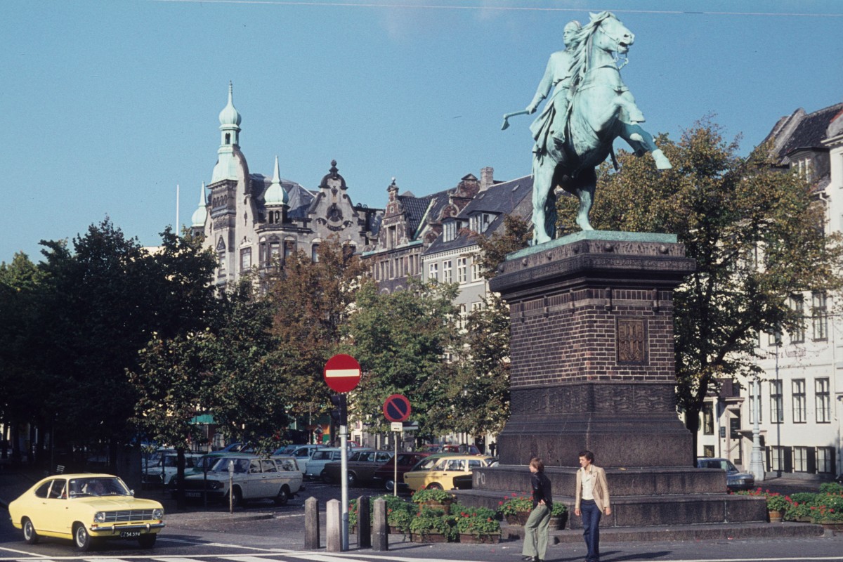 Kbenhavn / Kopenhagen eines Herbsttages in den 70er Jahren: Hjbro Plads (hjbro: 'Hohe Brcke') mit dem Denkmal fr den Bischof in Roskilde, Absalon (1128-1201), der 1167 eine Burg errichtete, wo sich jetzt das Schloss Christiansborg befindet. Darum betrachtet man Absalon als den Grnder der Stadt Kopenhagen. Es existierte zwar schon 1026 in diesem Gebiet eine Siedlung, aber erst 1186 wurde der Name Hafn erwhnt; in spteren Quellen findet man den Namen Kpmannhafn (= 'Kbmndenes Havn': 'Hafen der Kaufleute'). - Das Denkmal, ein Reiterstandbild, ist ein Werk des Bildhauers Vilhelm Bissen (Standbild) und des Architekten Martin Nyrop (Sockel). Es wurde 1902 aufgestellt.   