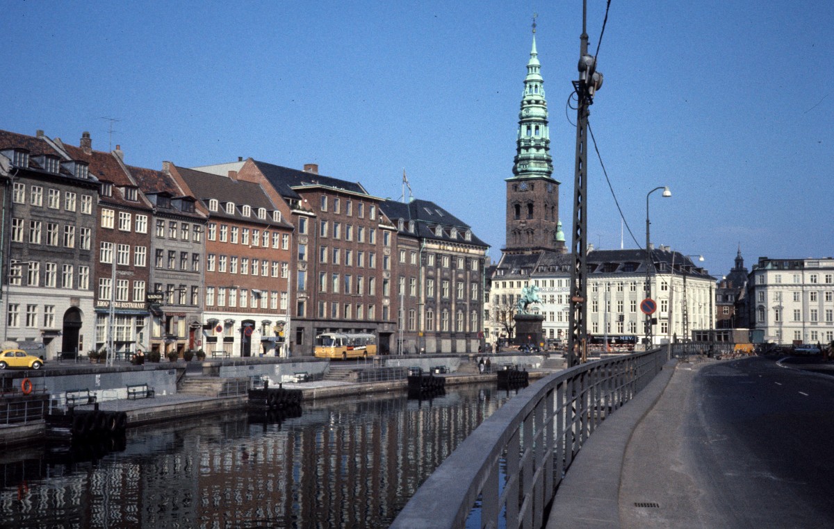 København / Kopenhagen eines Sommertages in den 1970er Jahren: Zu sehen sind die Strasse Gammel Strand (:  Altes Ufer ) auf der linken Seite des Kanals, ein Teil des Højbro Plads mit dem Reiterstandbild vom Bischof Absalon und der Turm der Sankt Nikolaj Kirke, die seit 1805 keinen kirchlichen Zwecken dient.
