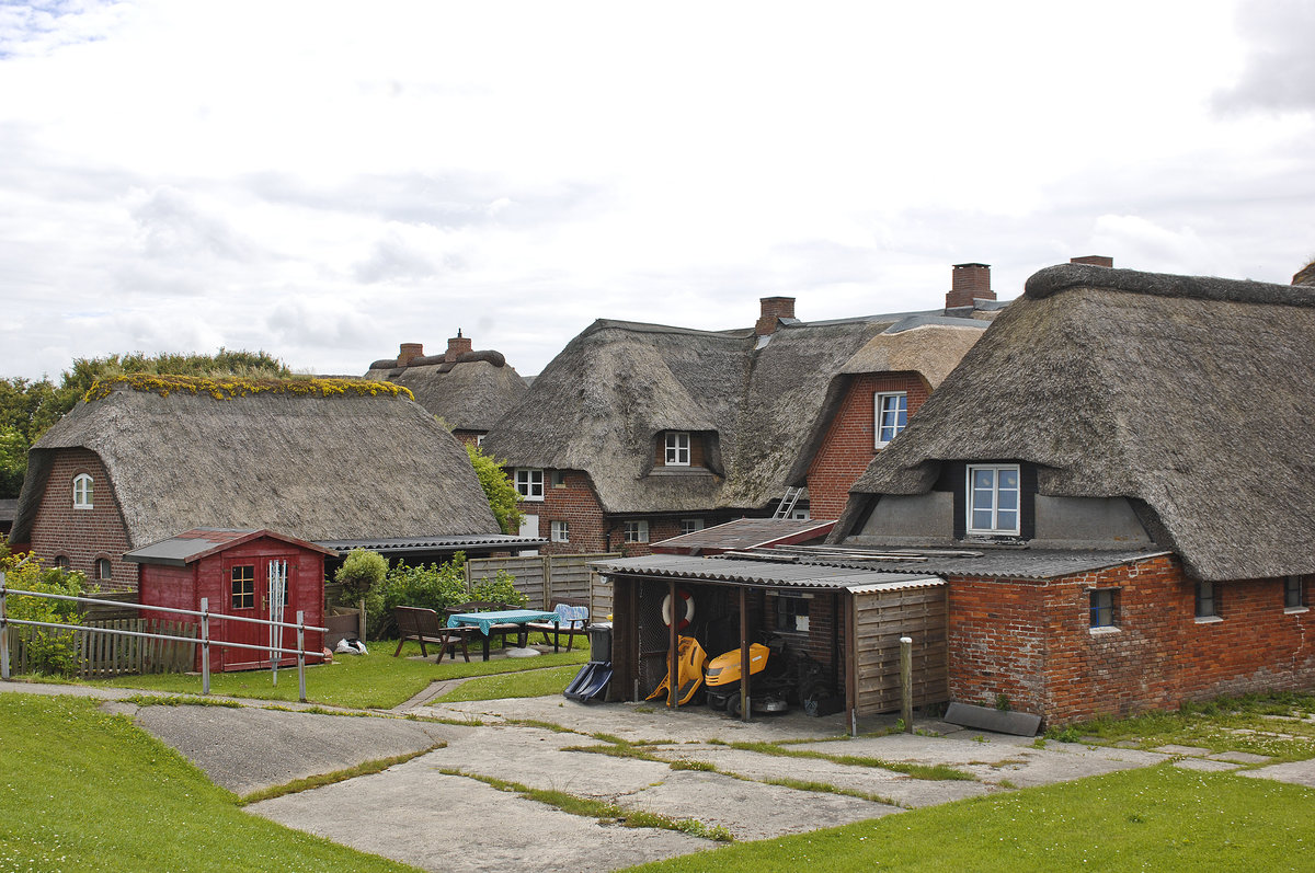 Land Dorf auf der Hallig Oland vom Deich aus gesehen. Die Halligen erheben sich nur wenige Meter ber dem Meeresspiegel, weshalb sie whrend einer starken Flut mit Ausnahme der Warften, knstlich aufgeschtteten Hgeln, auf denen die Huser stehen, bersplt werden („Landunter“). Aufnahme: 25. Juni 2017.