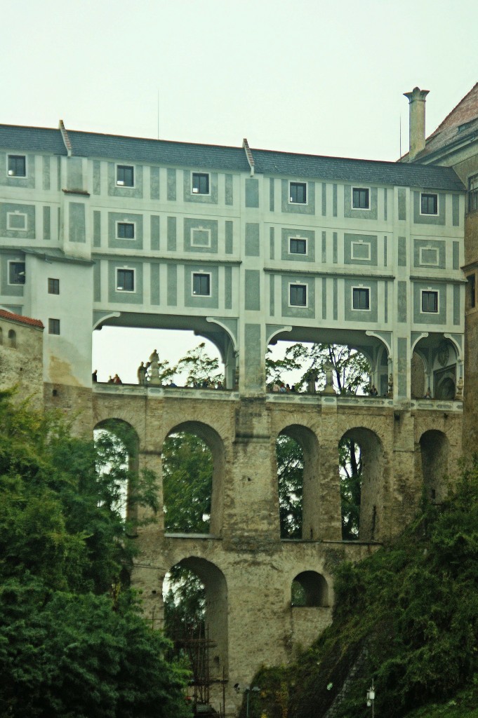 Schloss Česk Krumlov - Mantelbrcke  (14.9.2014)
Die Mantelbrcke ist eine mehrstckige Brcke in Česk Krumlov,die den Burggraben des dortigen Schlosses berspannt.
Der offene Durchgang verbindet zwei Hfe des Schlosses miteinander. Darber befinden sich zwei weitere geschlossene Stockwerke, mit einem weiteren Zwischengeschoss, die die Gebude auf beiden Seiten verbinden. Erstmals erwhnt wurde die Brcke im 15. Jahrhundert; das heutige Aussehen der Brcke stammt aus dem Jahr 1777. Zusammen mit dem Schloss zhlt die Brcke zum UNESCO-Welterbe.



