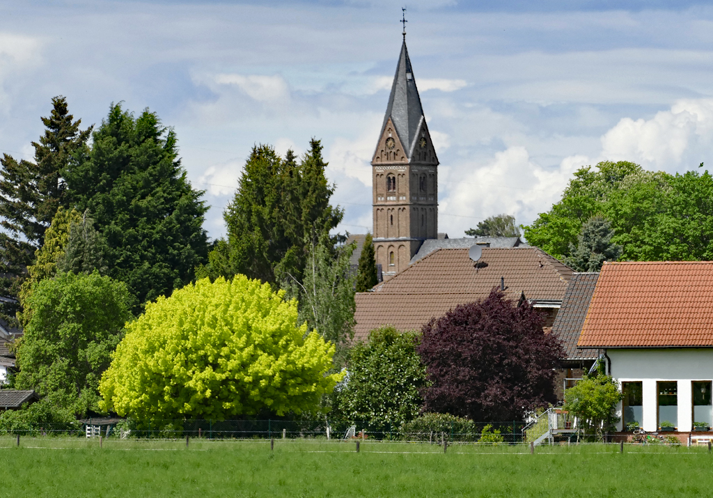 St. Medardus-Kirche, eingerahmt von blhenden Bumen, in Eu-Wikirchen - 10.05.2017