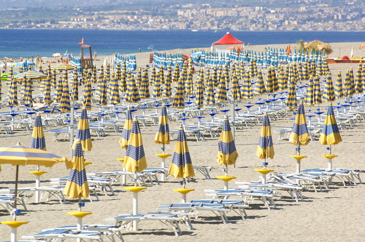 Strand am Giardini-Naxos. Im Hintergrund die Stadt Giarre. Aufnahme: Juli 2013.