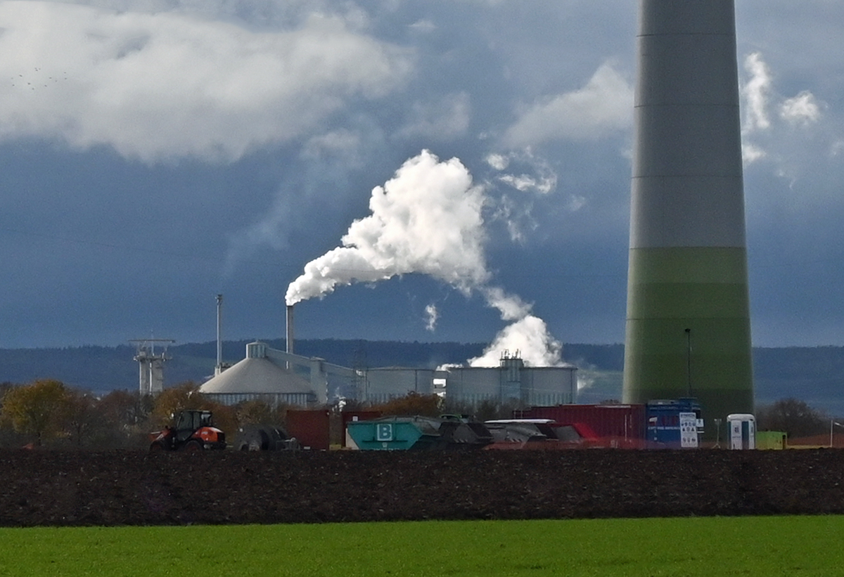 Teleblick auf die Zuckerfabrik Euskirchen, die  unter Volldampf whrend der Rbenkampagne luft. Rechts im Bild ein mchtiger Pfeiler eines Windkraftrades - 04.12.2020