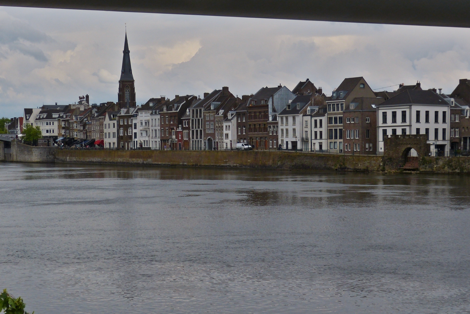 Blick vom linken Maas Ufer unter der Fugngerbrcke hindurch, auf die Uferpromenade auf der rechten Flussseite in Maastricht. 05.2023