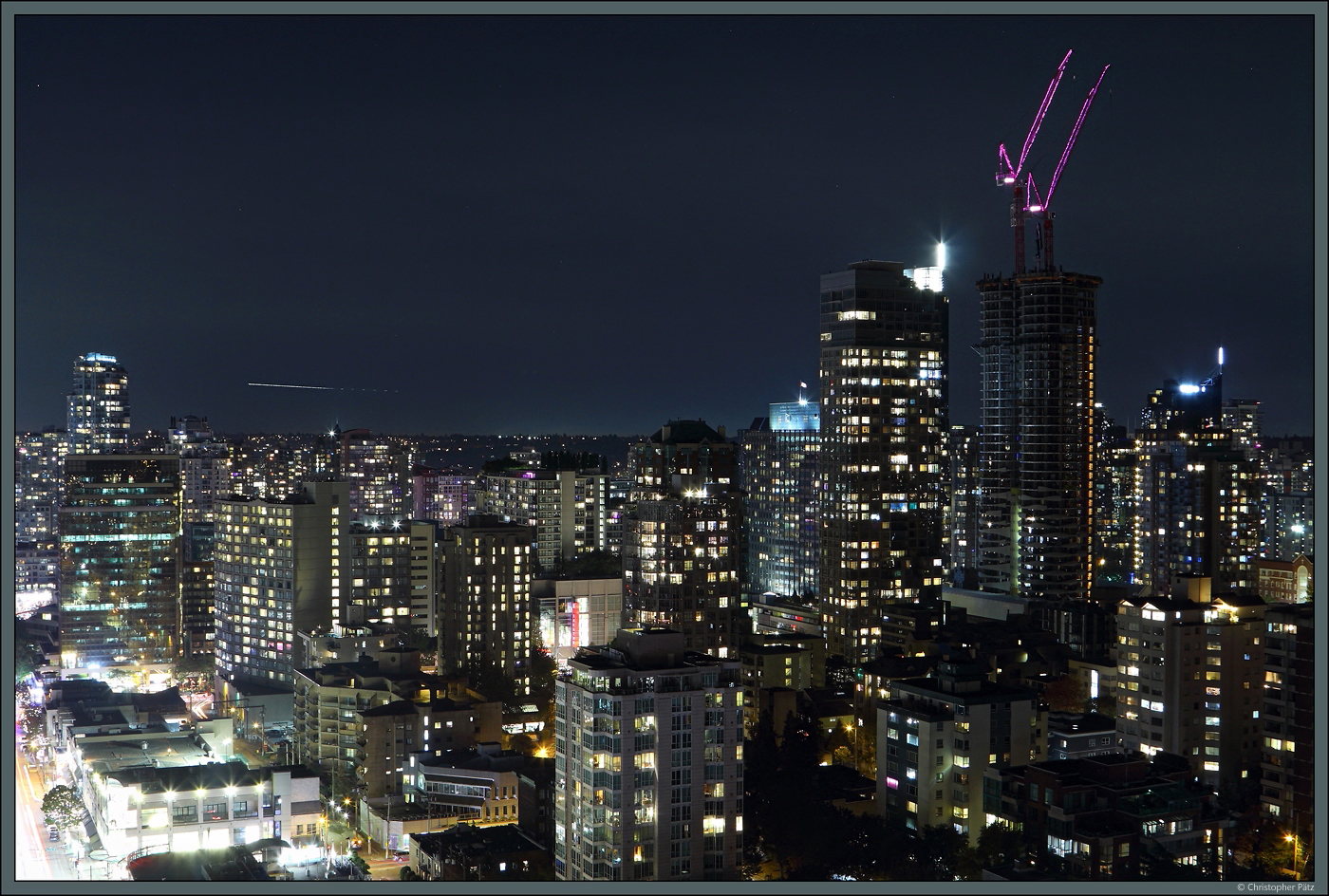 Die Skyline der Downtown von Vancouver bei Nacht, aufgenommen aus dem Blue Horizon Hotel. Am linken Bildrand verluft die Robson Street. Recht ist das im Bau befindliche Hochhaus  The Butterfly  zu sehen. (Vancouver, 15.10.2022)