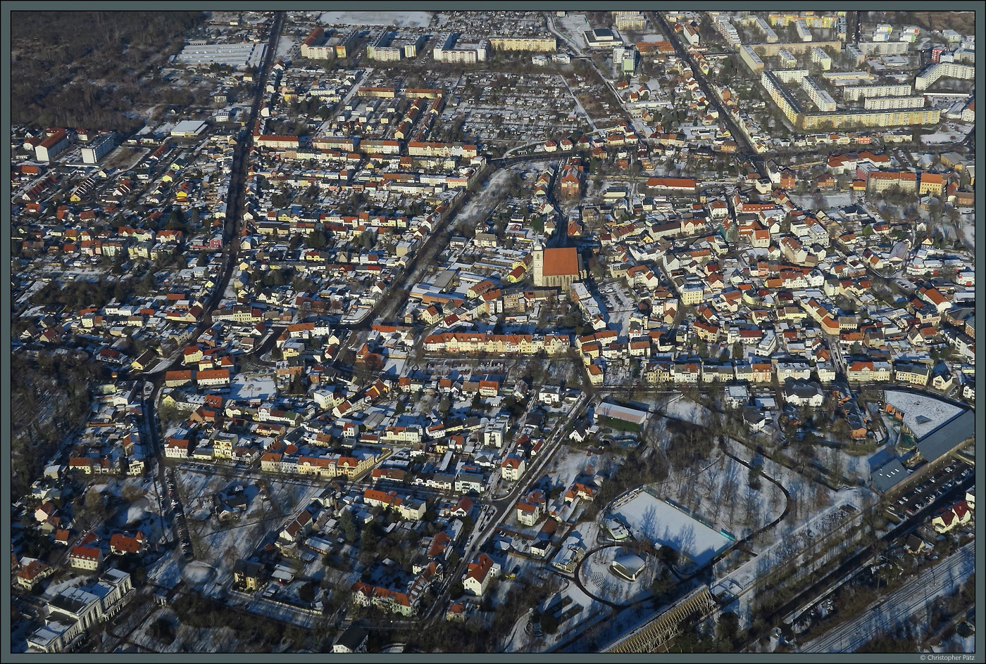 Die Stadt Schnebeck entstand 1932 durch Zusammenschluss dreier Orte. Im Sdwesten liegt der Stadtteil Bad Salzelmen, der wiederum selbst durch den Zusammenschluss der zwei Orte Gro Salze und Elmen. Rund um die Kirche St. Johannis sind Teile des alten Ortskerns von Gro Salze erhalten geblieben. Am unteren Bildrand ist der Kurpark zu sehen. Nrdlich an Bad Salzelmen schlieen sich verschiedene Neubaugebiete an. (20.01.2024)